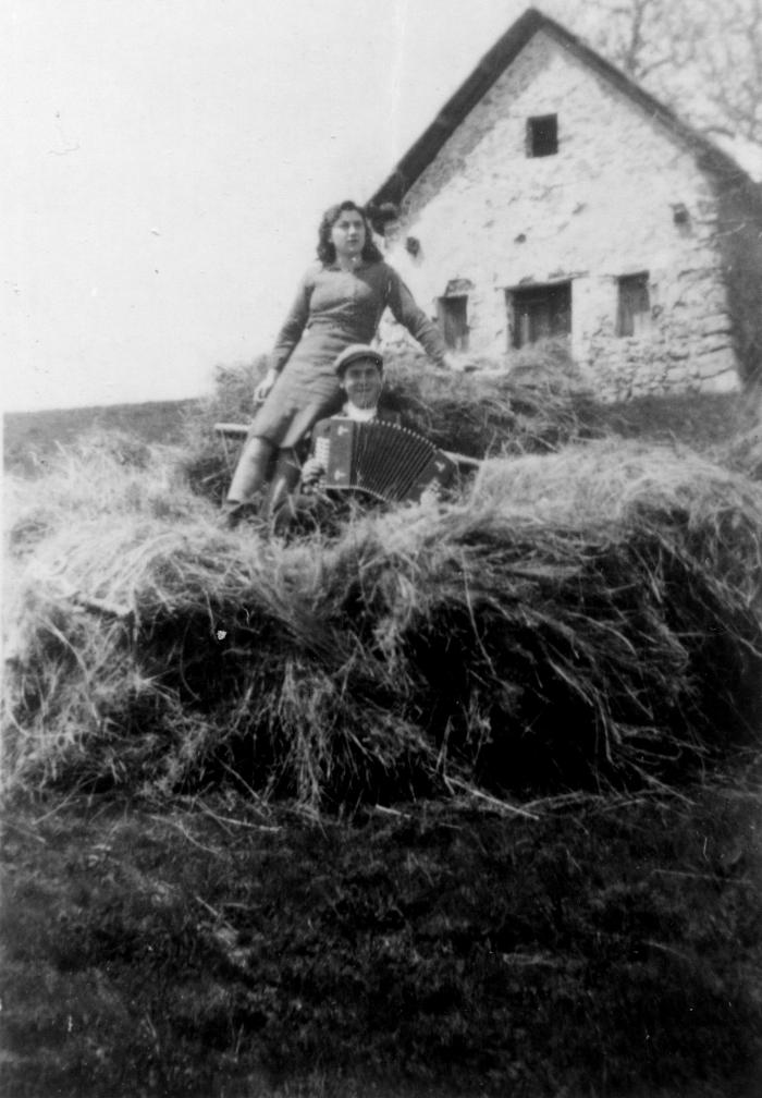 [Homme jouant de l'accordéon et jeune femme dans du foin. Bouchanières ?]
