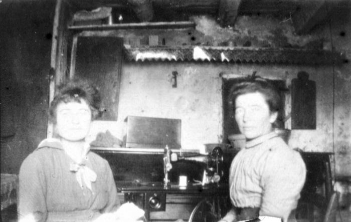 [Portrait de deux femmes entre une machine à coudre, Barels.]