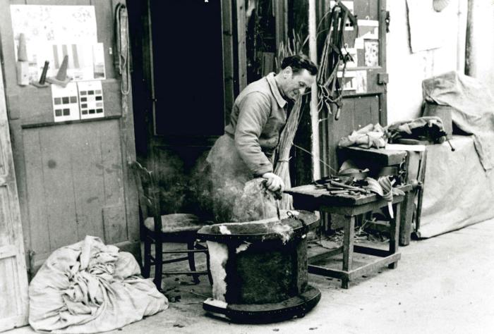 Jean Ros fabriquant un bât : perçage des trous à chaud à travers la paille de seigle et la peau pour retrouver les trous de fixation des cordes sur les arceaux.