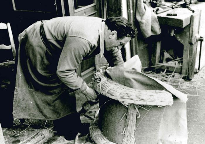 Jean Ros fabriquant un bât : habillage du bât avec de la paille