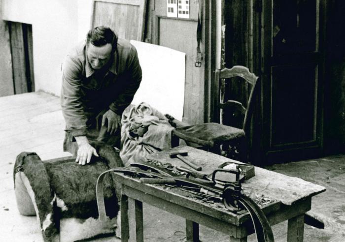 Jean Ros fabriquant un bât : Couture d'une peau de veau pour l'habillage terminée, reste à clouer des lanières de cuir pour protéger la peau au niveau des arceaux.