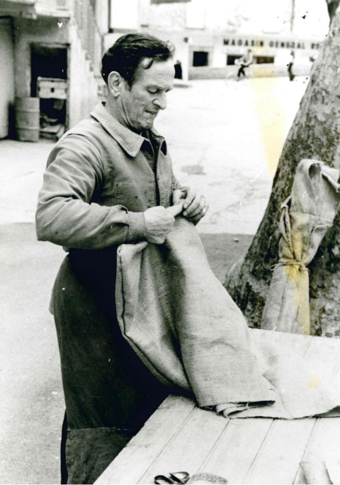 Jean Ros fabriquant un bât : découpage de la toile des coussinets supérieurs